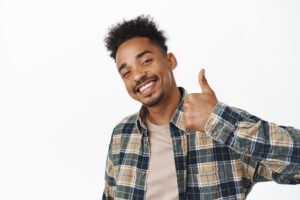 Portrait of pleased african american man smiling satisfied, say yes, showing thumb up in approval, encourage you did great job, praise nice choice, white background.